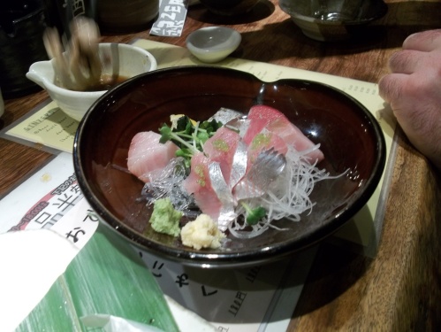 Sashimi of different kinds of fish in a bowl.